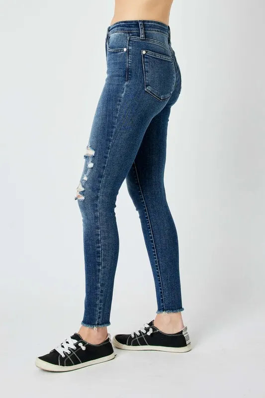 Dark blue skinny jeans rear view with frayed hem and small ripped spot near left leg