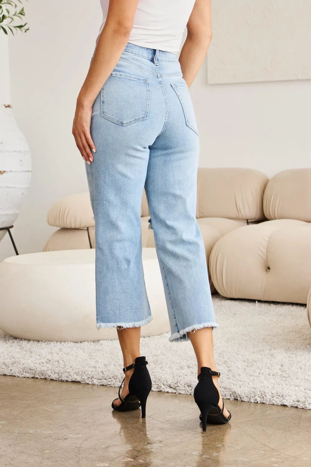 Light wash high-waist jeans with frayed hem and back pockets, straight cropped fit