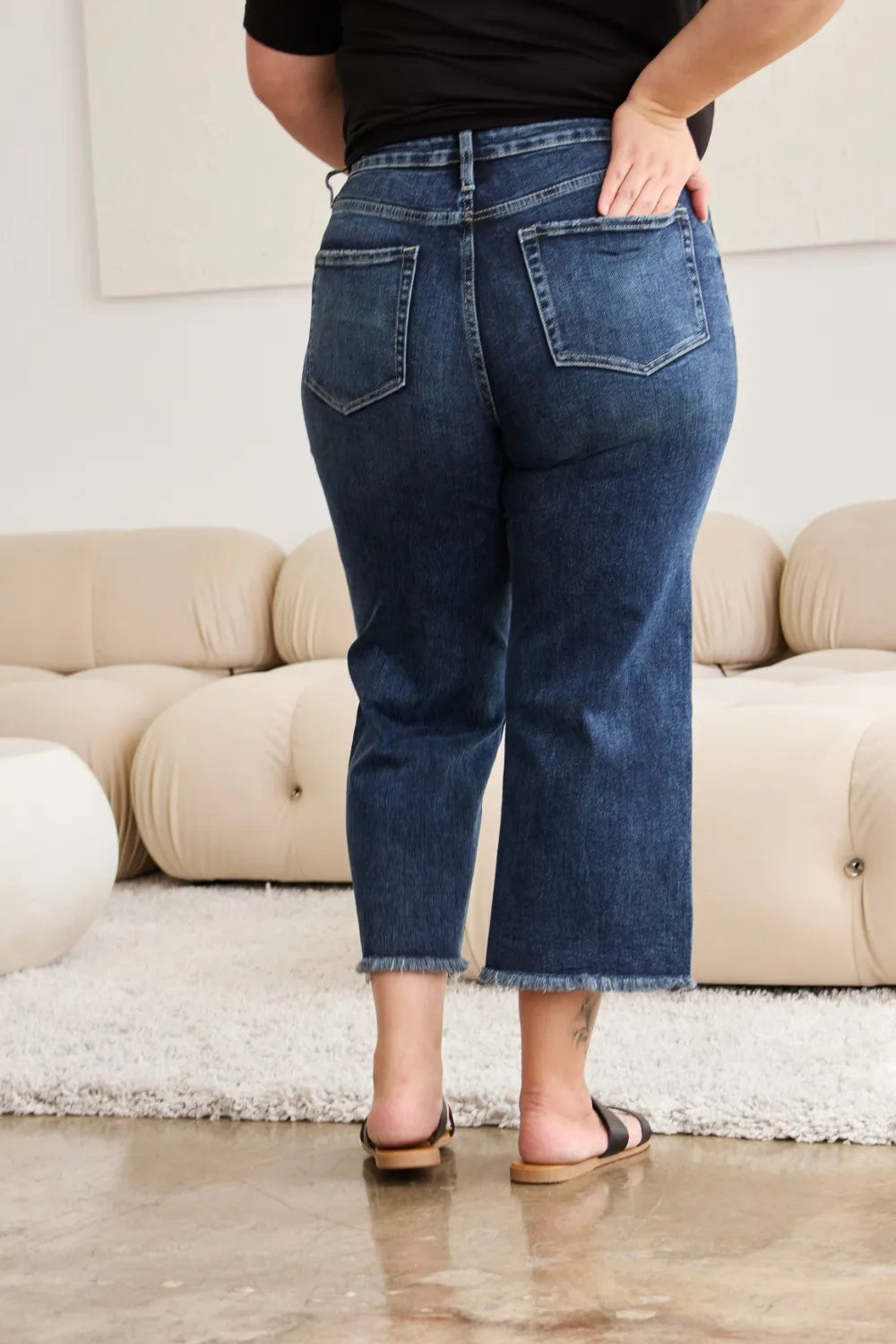 Back view: high-waist raw hem jeans with dark blue wash and back pocket stitching