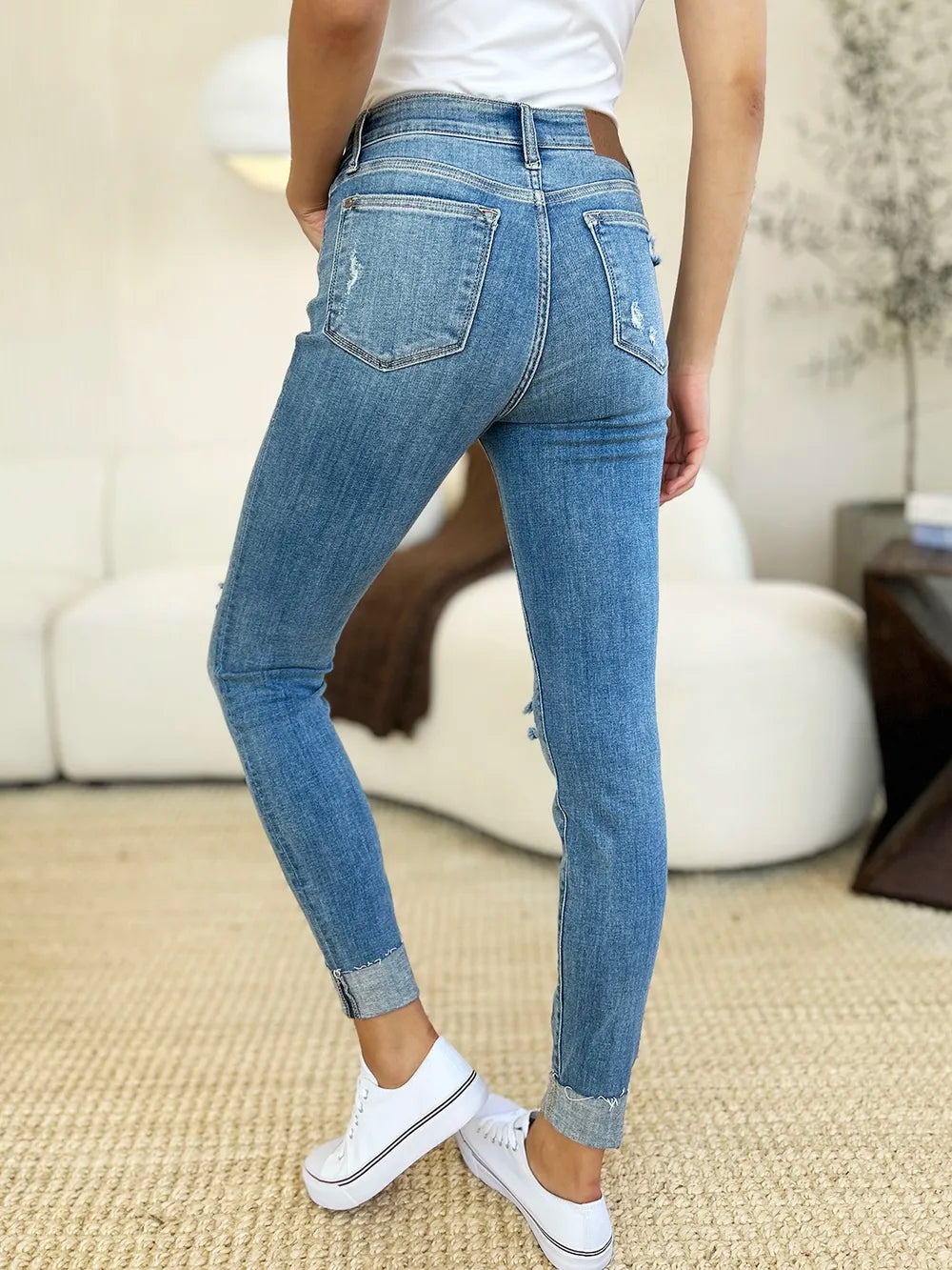Rear view: medium wash mid rise skinny jeans with back pocket and cuffed hem