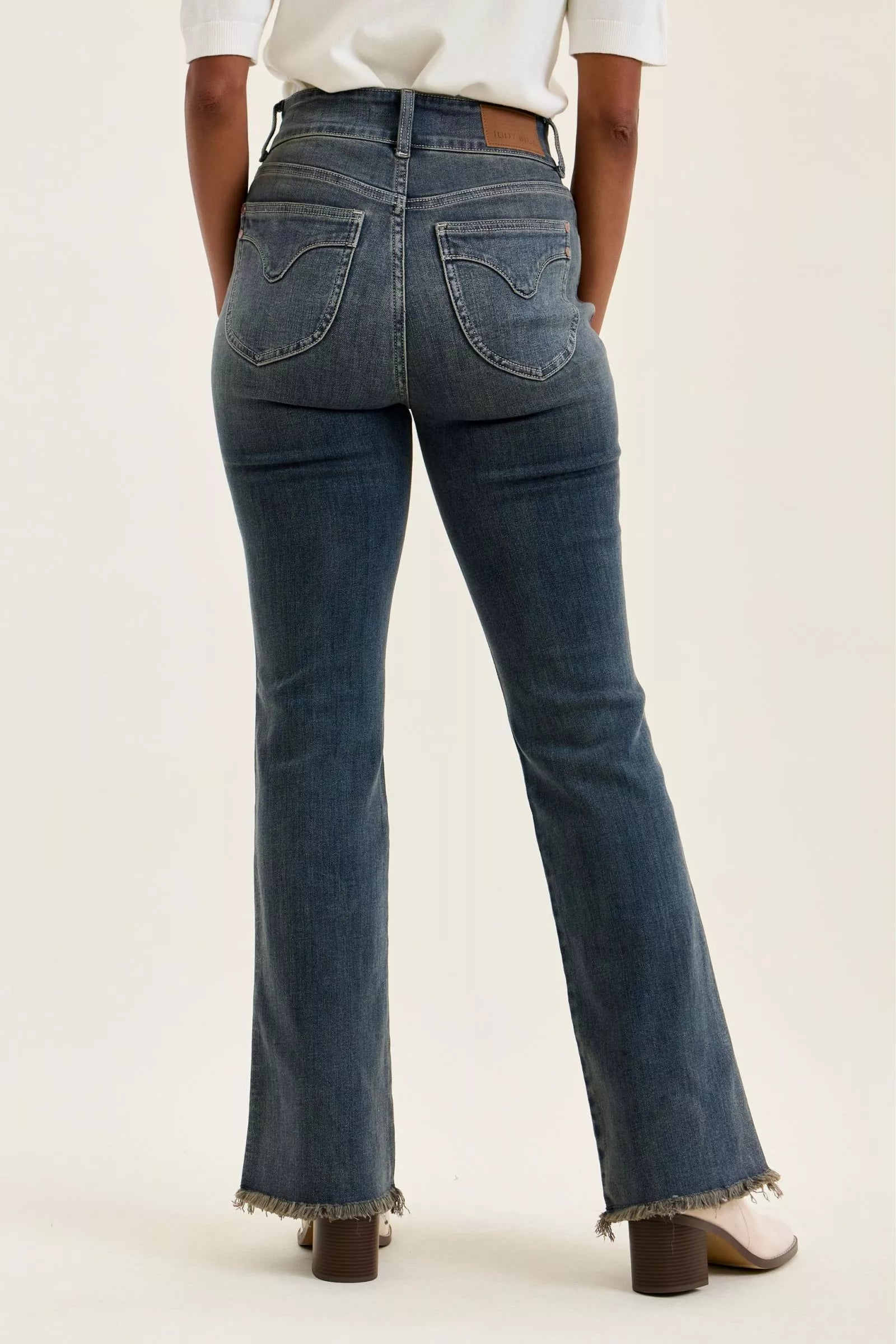 Back view of high-waist dark denim jeans with frayed ankle hem and seamed pockets.