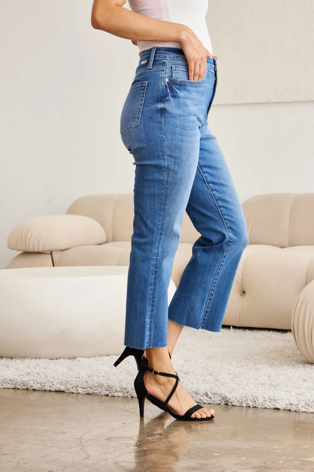 Back/side view of medium blue high-waist tummy-control jeans with cropped hem and belt loops