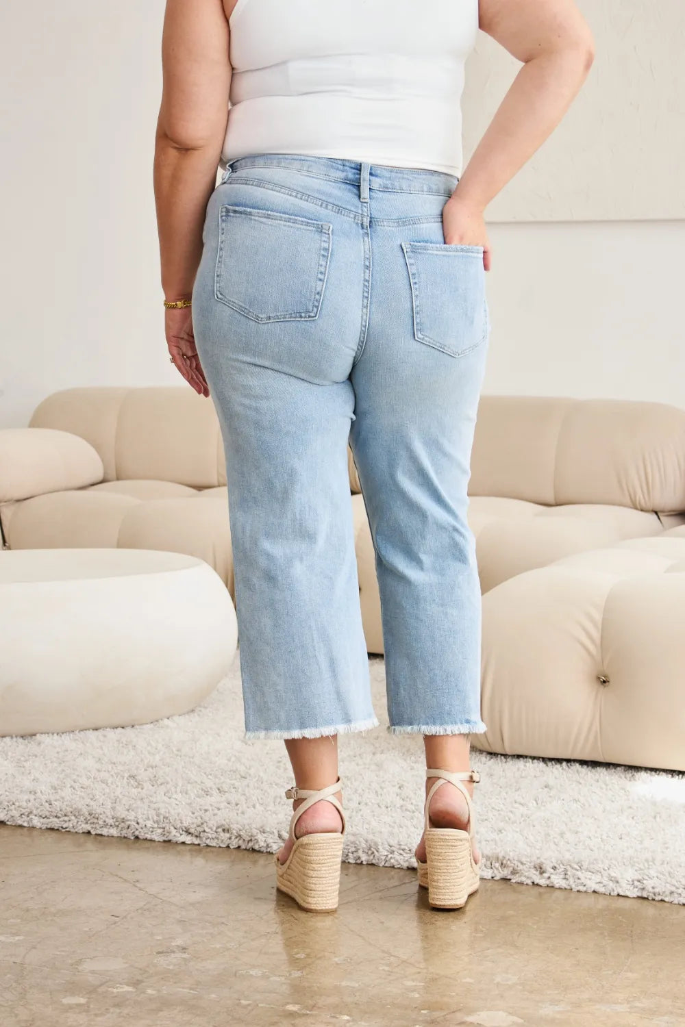 Light wash high-rise straight jeans with raw hem and back pockets detail