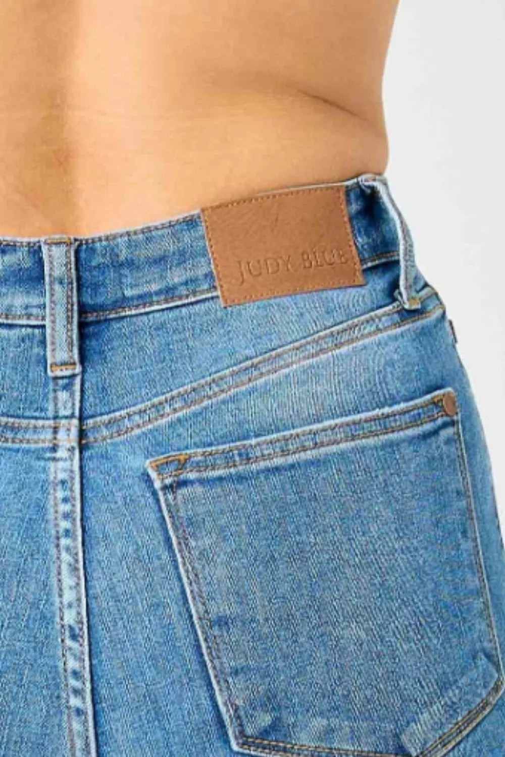 Waistband label on medium-blue high-waisted flare jeans, button closure