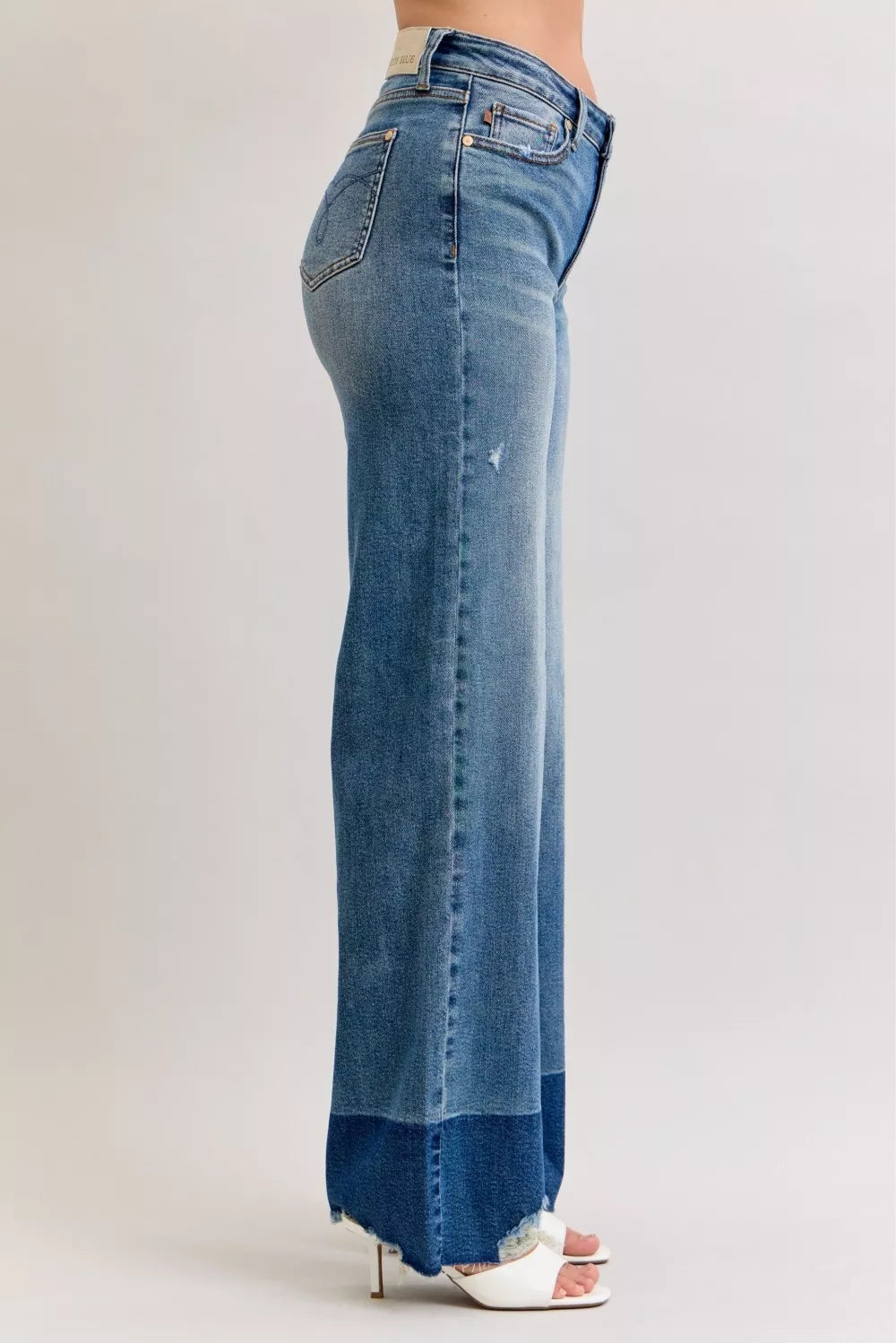High-waist straight jeans side view in dark denim with raw frayed cuffs and back pocket