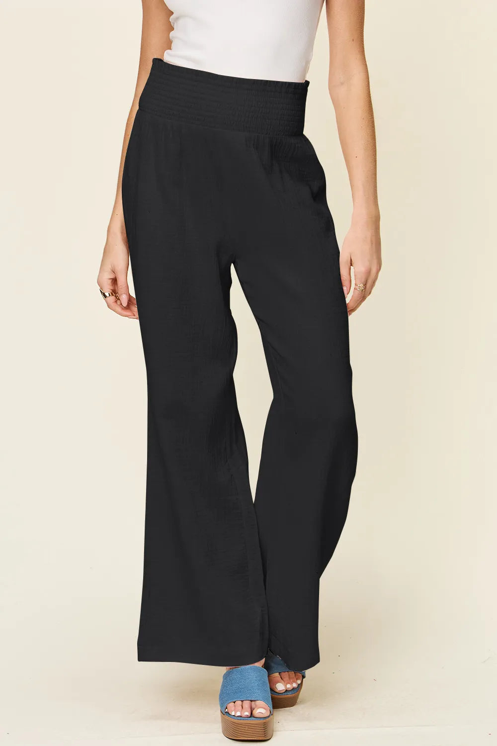 Black smocked-waist wide-leg pants, front view, textured woven fabric