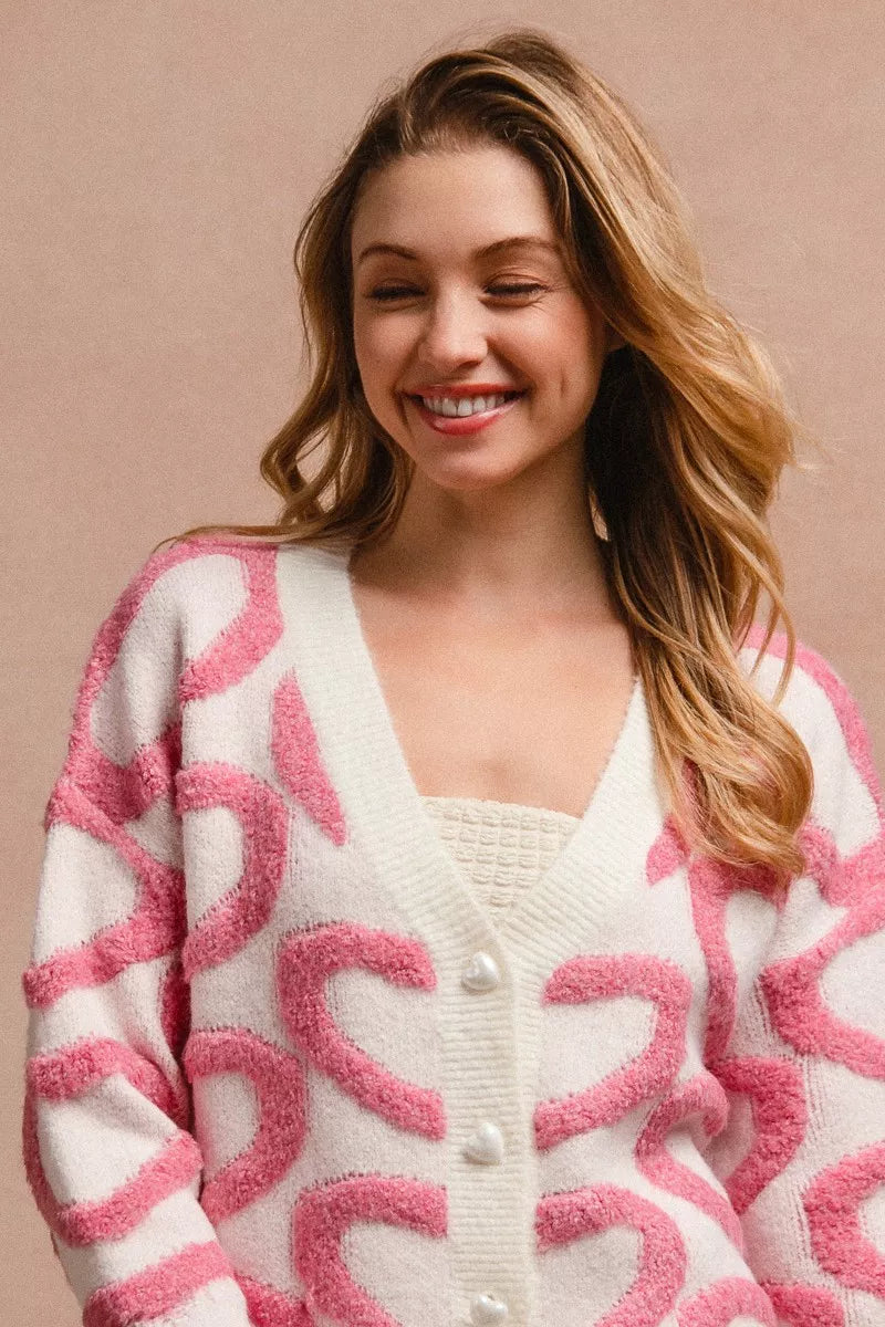 Pink and white heart-pattern cardigan with V-neck and visible button placket, long sleeves