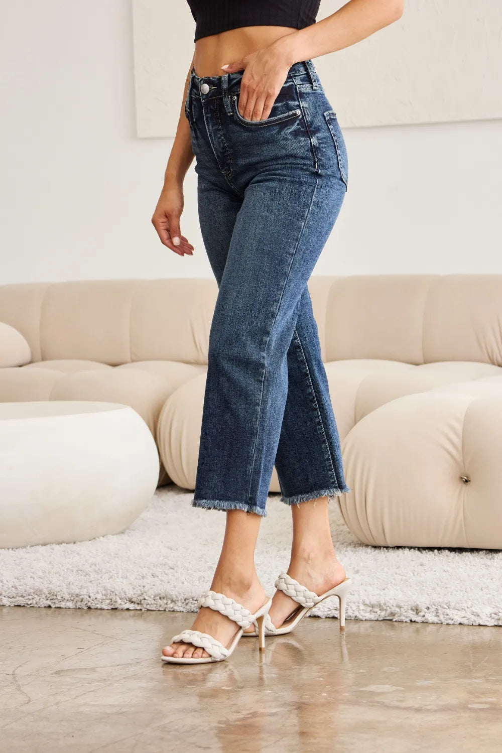High-waist dark-wash jeans showing back yoke and stitched pockets, raw cuff hem