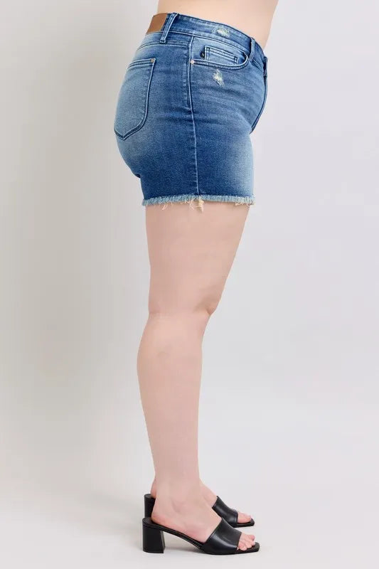 Blue denim shorts, side view: cuffed leg with frayed edge and flap pocket