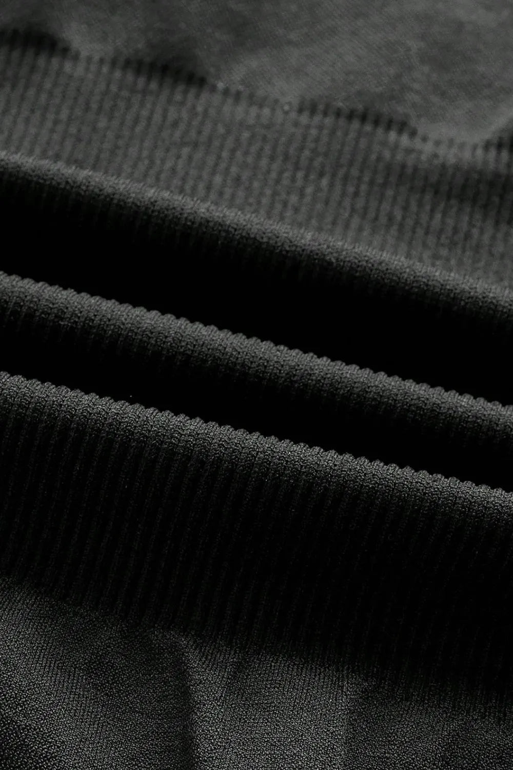 Black bodysuit fabric close-up with ribbed stretch texture