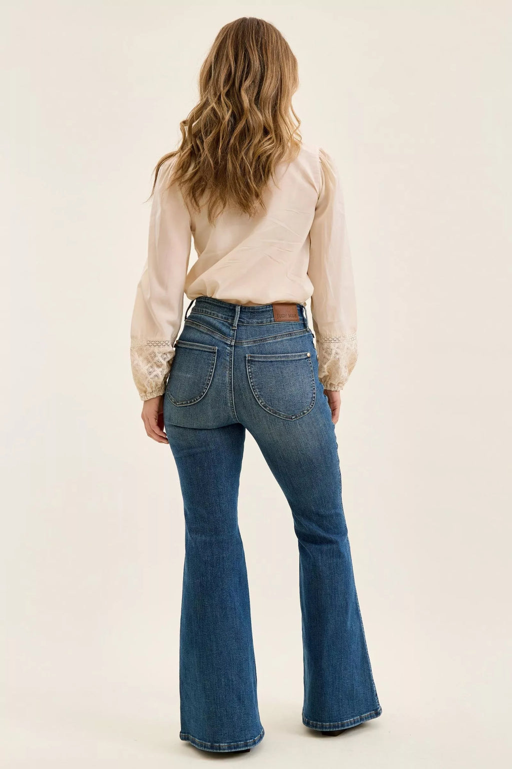 Dark denim high-waist flare jeans, back view with curved pockets and center seam