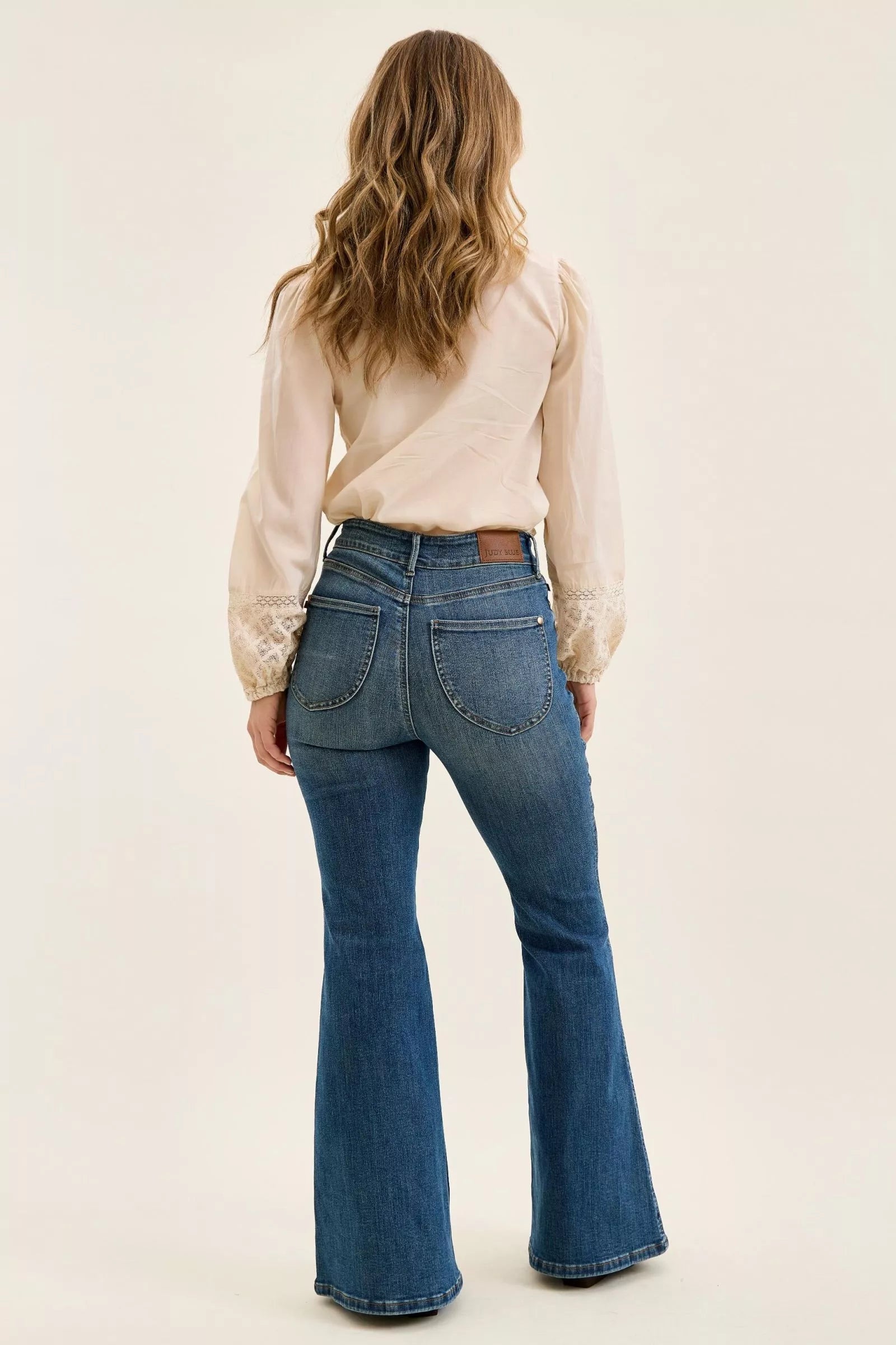 Dark denim high-waist flare jeans, back view with curved pockets and center seam