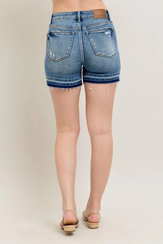 Back/side view of vintage wash denim shorts with frayed hem and patch pockets