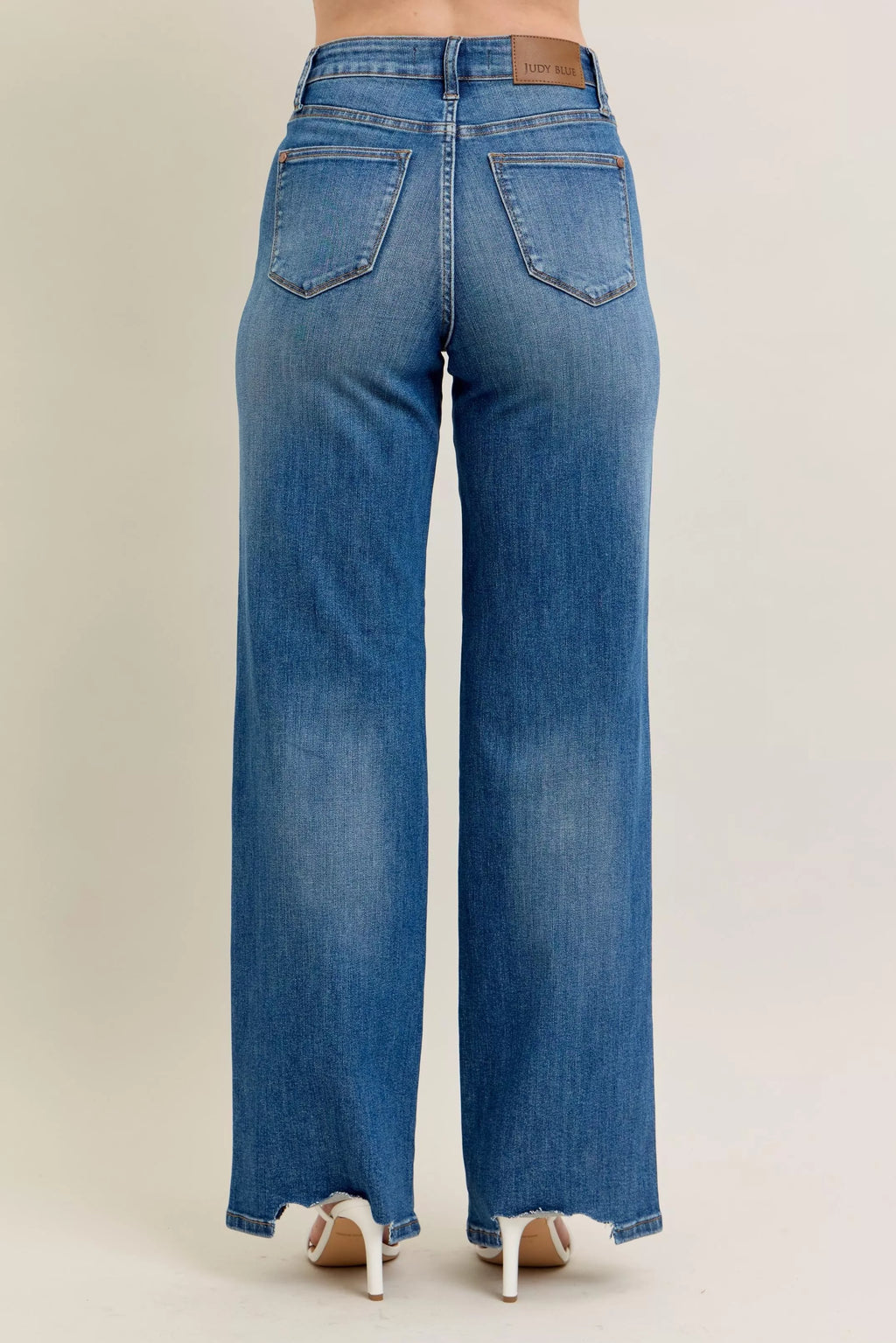 Back view: medium-wash wide-leg jeans with two back pockets and frayed hem