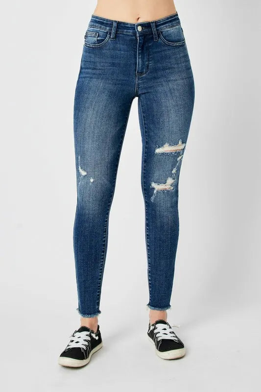 Dark blue high-waist skinny jeans with two front knee distress patches and frayed hems