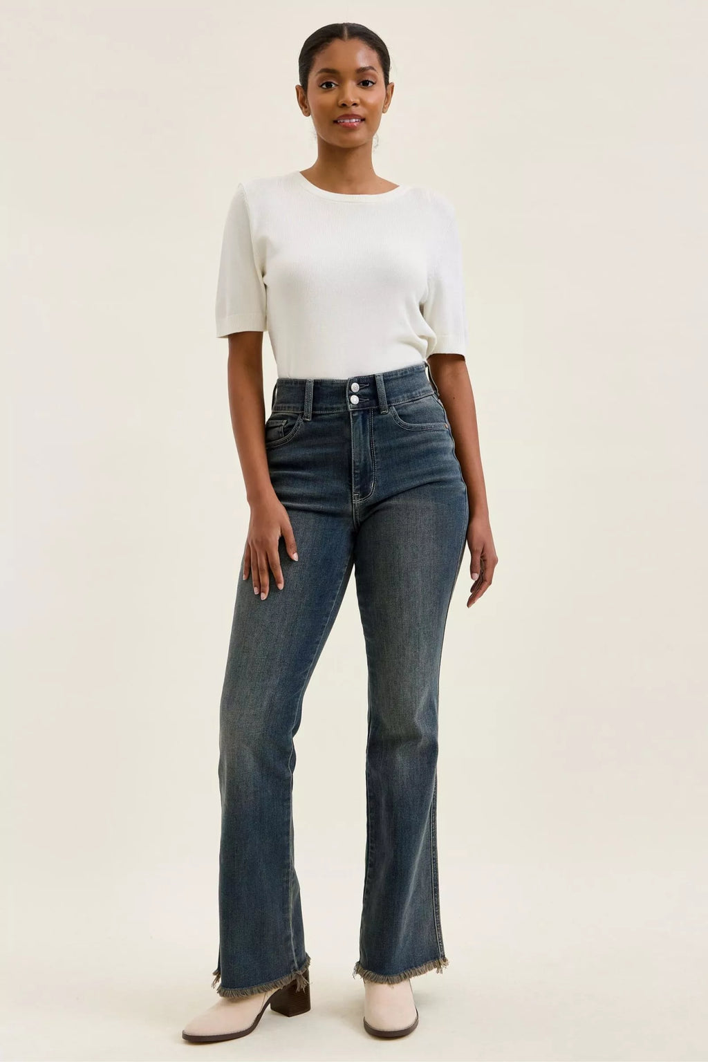 High-waist dark denim jeans featuring double-button front and frayed hem at ankle length.