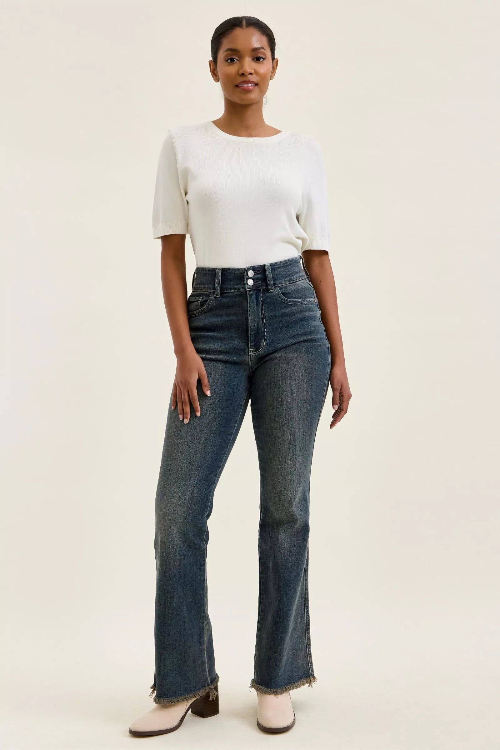 High-waist dark denim jeans featuring double-button front and frayed hem at ankle length.