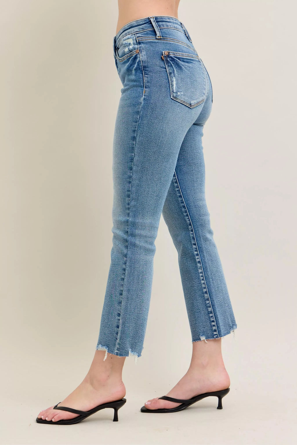 Medium-wash kick flare jeans, back view with frayed destroy hem
