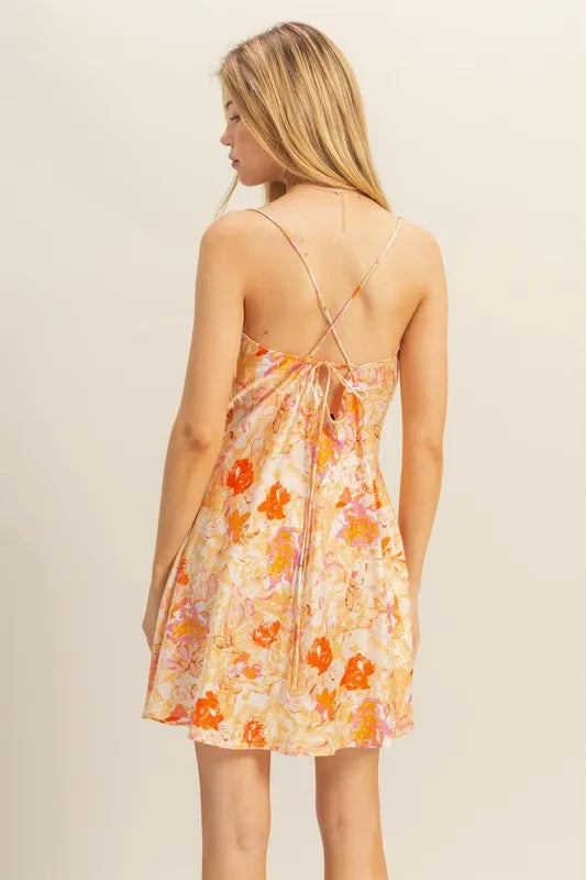 Back view of floral satin mini dress; crisscross straps, orange floral print on cream