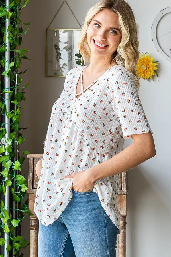 Flowy babydoll top in white ditsy floral print with crisscross V neckline